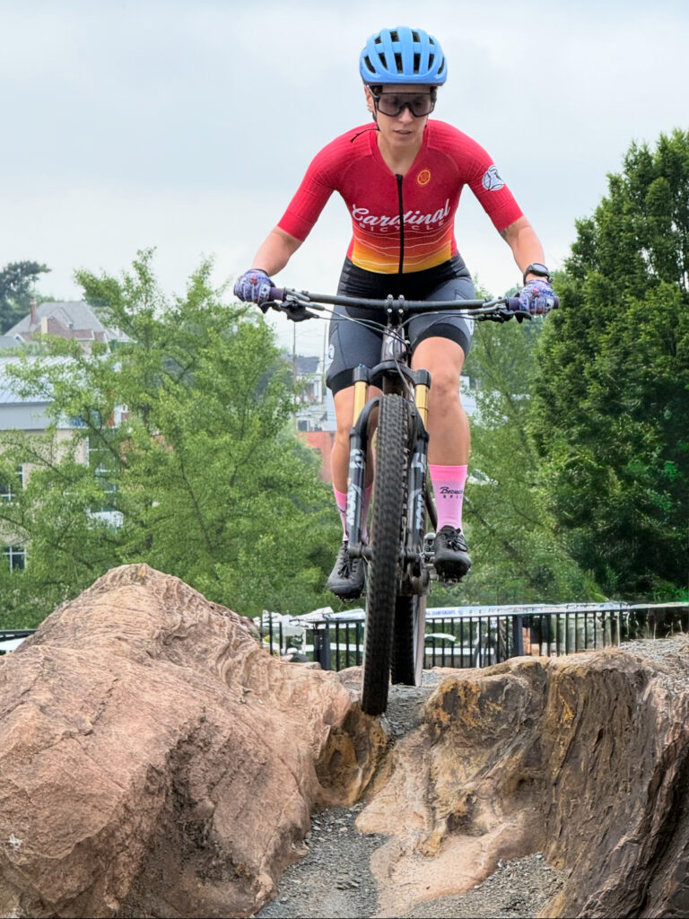 Reference photo for Take Flight: a mountain biker in a red jersey riding off a boulder at Elmwood Park in Roanoke, Virginia