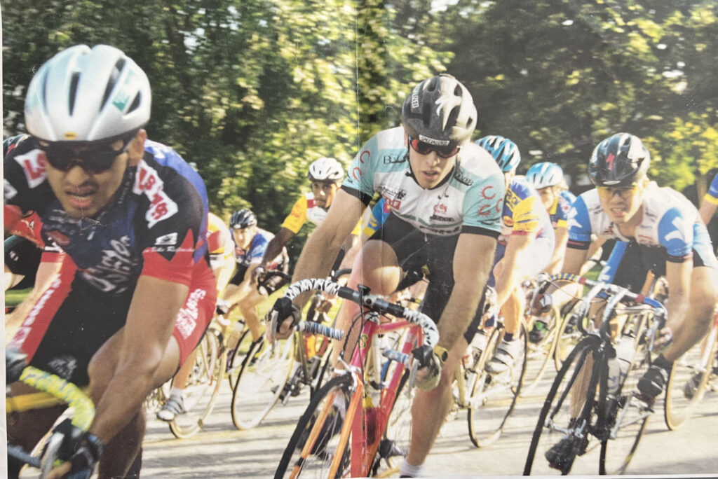 Reference photo for The Good Race: a pack of road cyclists leaning through a corner in a 1991 criterium